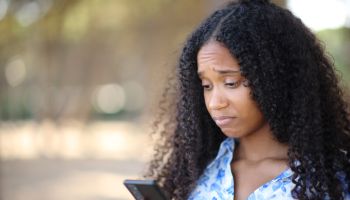 Disappointed black woman checking cell phone