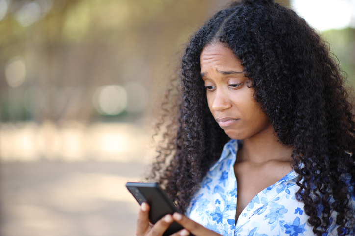 Disappointed black woman checking cell phone