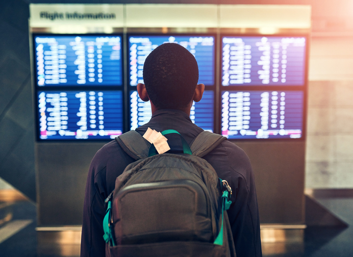 Backpack, travel and man at airport for schedule or reading flight timetable on vacation. Bag, back or person at airline to check departure information on boarding gate with luggage for holiday trip