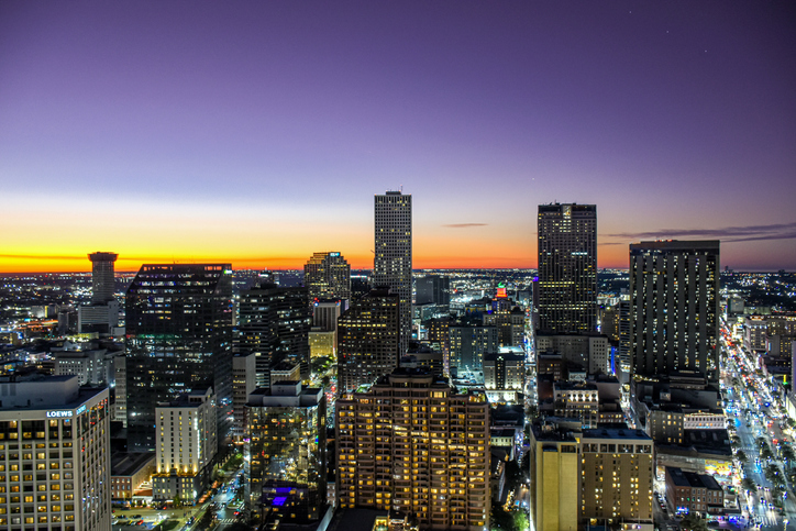 Majestic aerial "skyline" of New Orleans ("Nola") at sunset (golden hour) with Canal street traffic and skyscrapers illuminated at dusk in Louisiana, USA