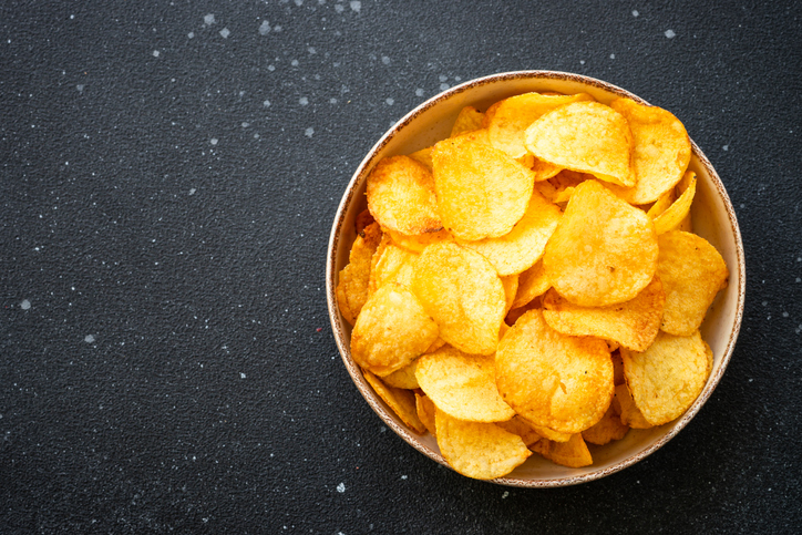 Potato chips and ketchup on black table. Top view.