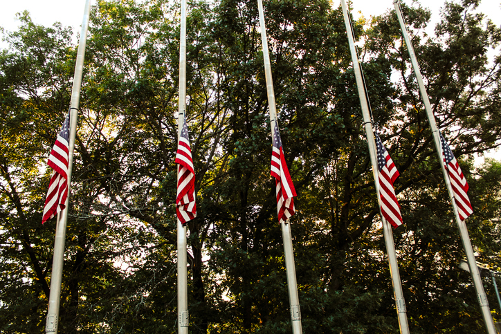 Looking up at American flags flying at half-staff patriotic background.