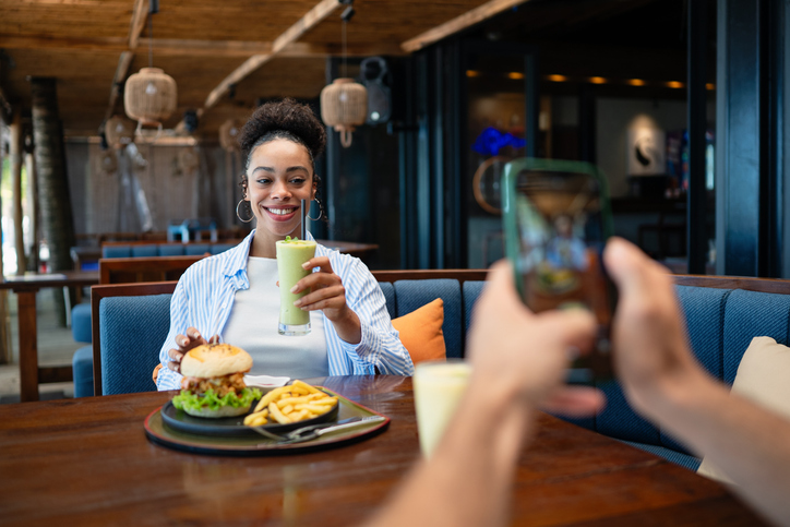 Young couple sharing dining experience at tropical restaurant, engaging with their online followers