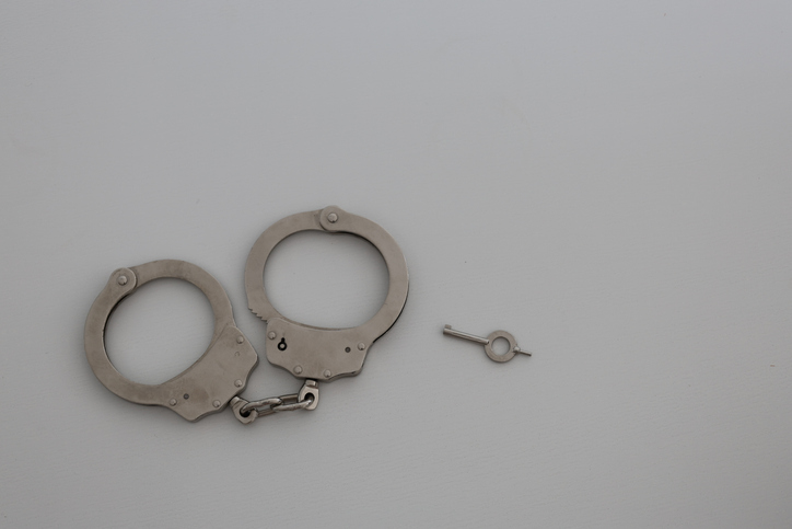 Handcuffs and key placed on white background minimal composition