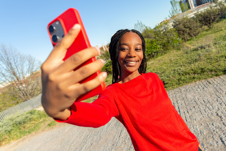 Young black woman taking selfie with red smartphone