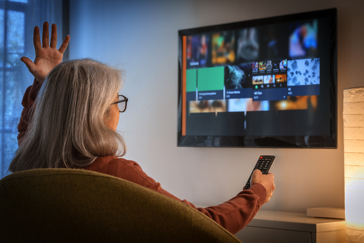 Senior woman struggling with streaming service on television