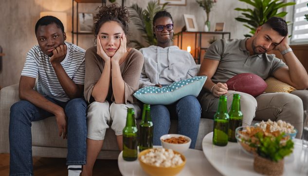 Bored group of friends watching disappointing game on TV